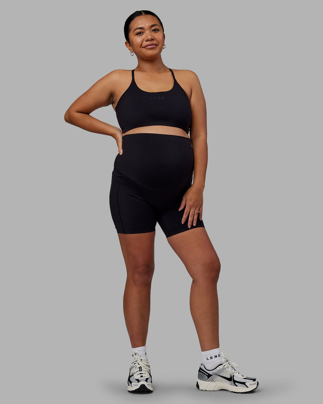 Woman wearing Elixir Ultra High-Rise Maternity 6" Short Pockets - Black | Model:Jojo | Size:M
