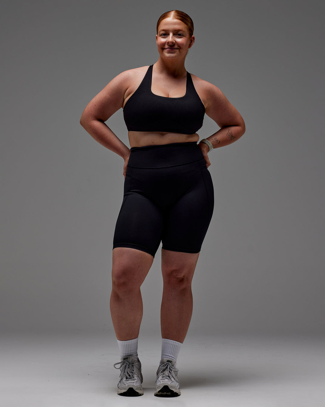 Woman wearing Fusion Ultra High-Rise 9" Short Pockets - Black | Model:Caity | Size:M