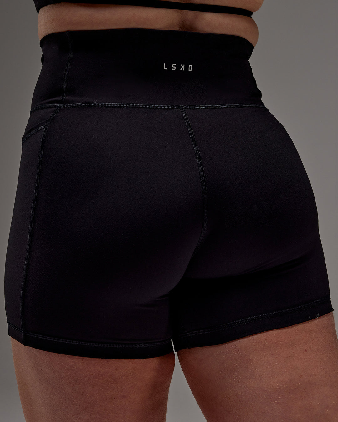 Woman wearing Fusion Ultra High-Rise 6" Short Pockets - Black | Model:Caity | Size:M