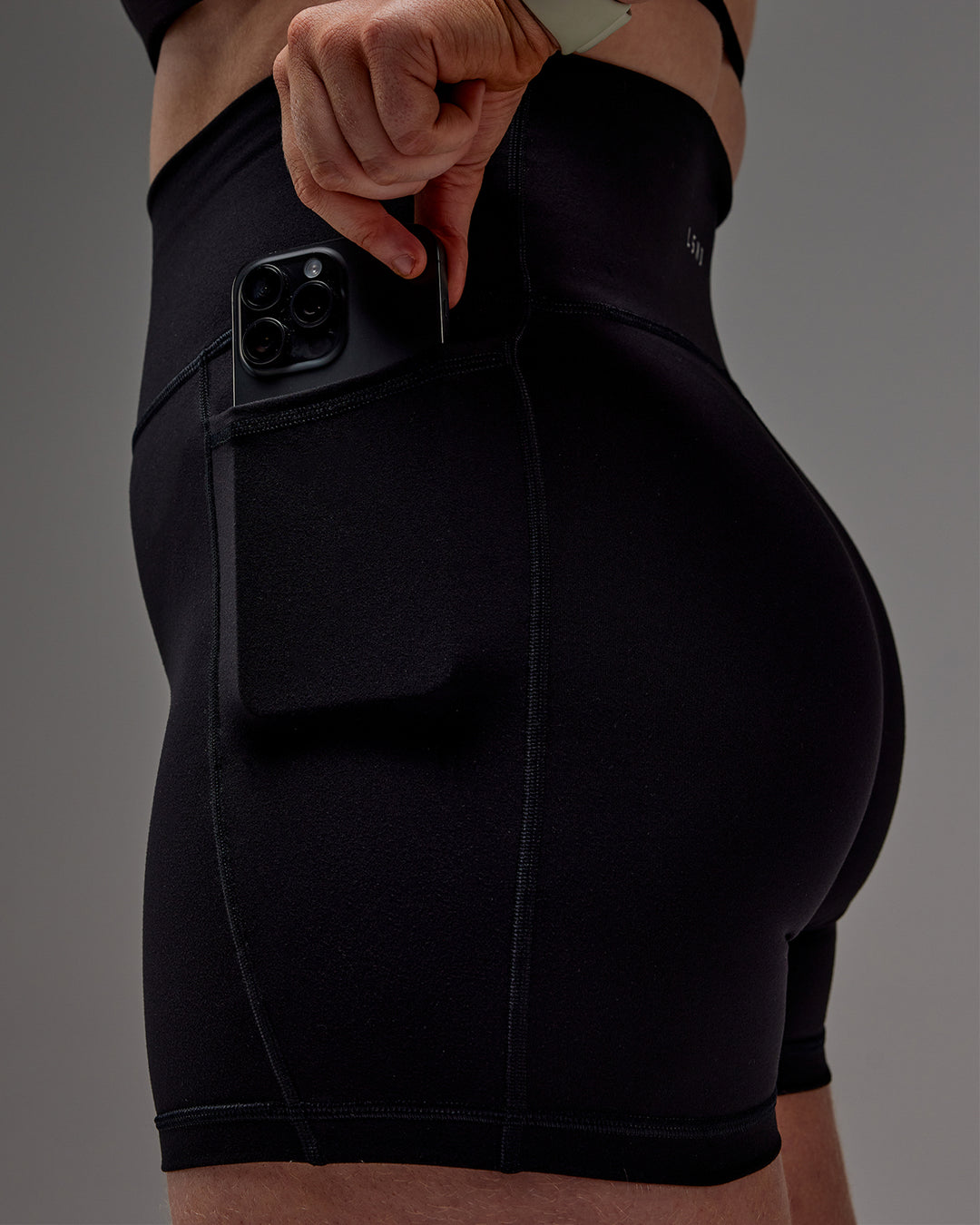 Woman wearing Fusion Ultra High-Rise 6" Short Pockets - Black | Model:Caity | Size:M