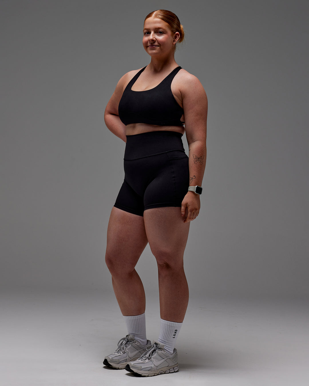 Woman wearing Fusion Ultra High-Rise 4" Short Pockets - Black | Model:Caity | Size:M