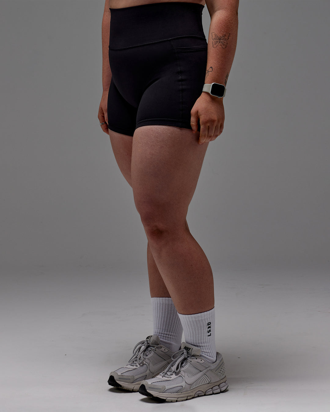 Woman wearing Fusion Ultra High-Rise 4" Short Pockets - Black | Model:Caity | Size:M