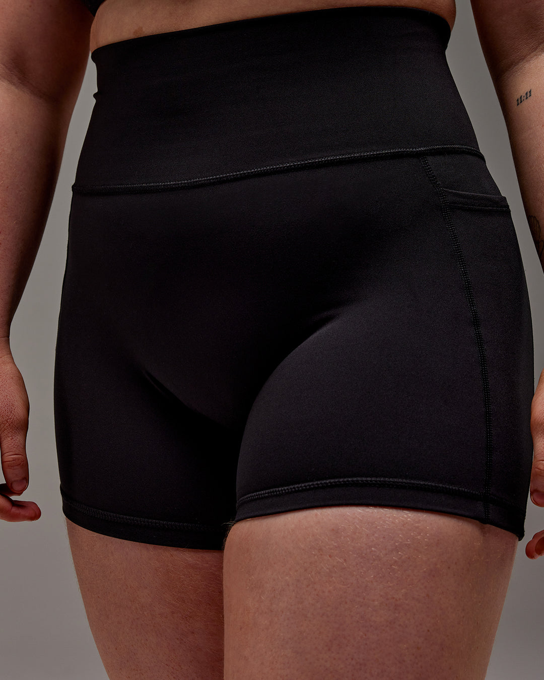 Woman wearing Fusion Ultra High-Rise 4" Short Pockets - Black | Model:Caity | Size:M