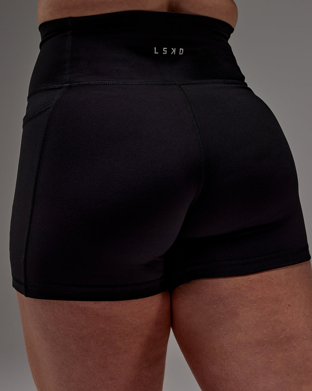 Woman wearing Fusion Ultra High-Rise 4" Short Pockets - Black | Model:Caity | Size:M