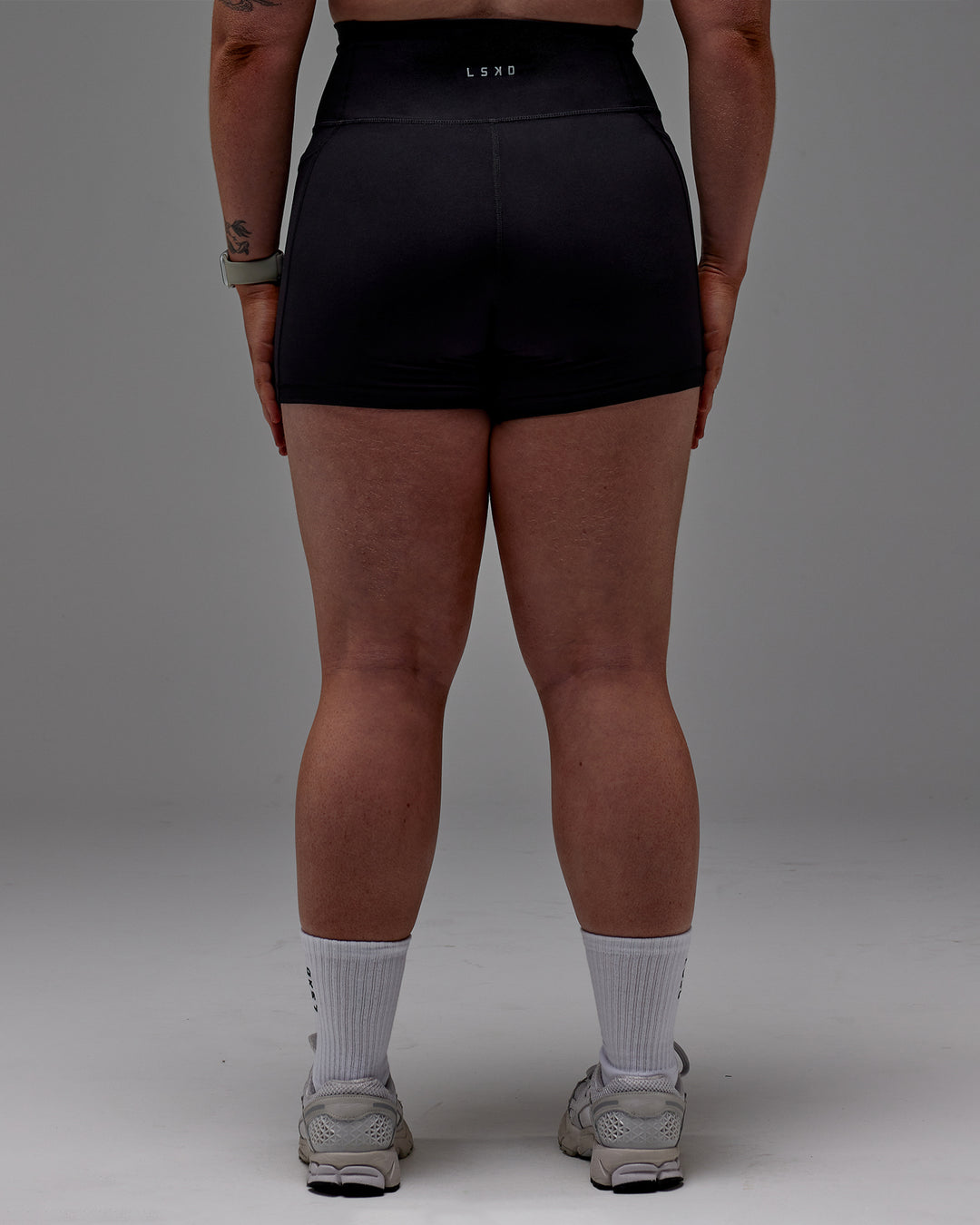 Woman wearing Fusion Ultra High-Rise 4" Short Pockets - Black | Model:Caity | Size:M