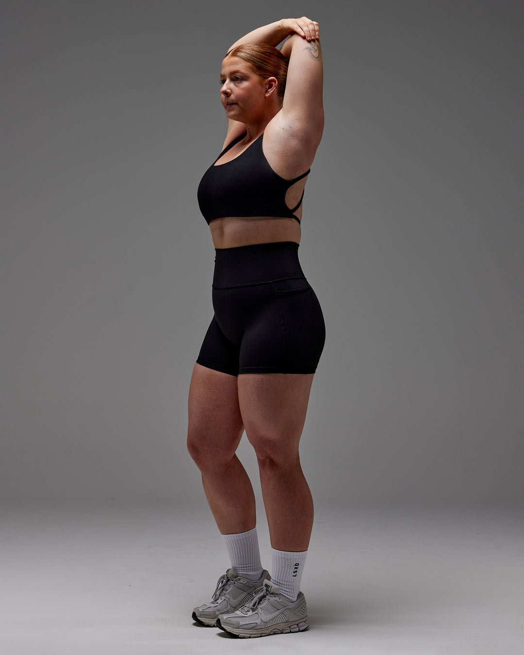 Woman wearing Fusion Ultra High-Rise 4" Short Pockets - Black | Model:Caity | Size:M