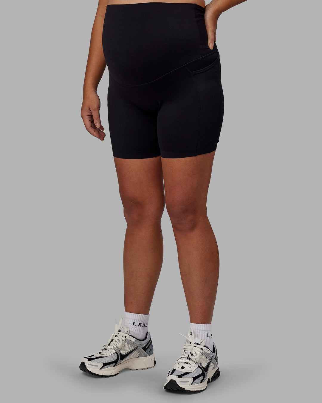 Woman wearing Elixir Ultra High-Rise Maternity 6" Short Pockets - Black | Model:Jojo | Size:M