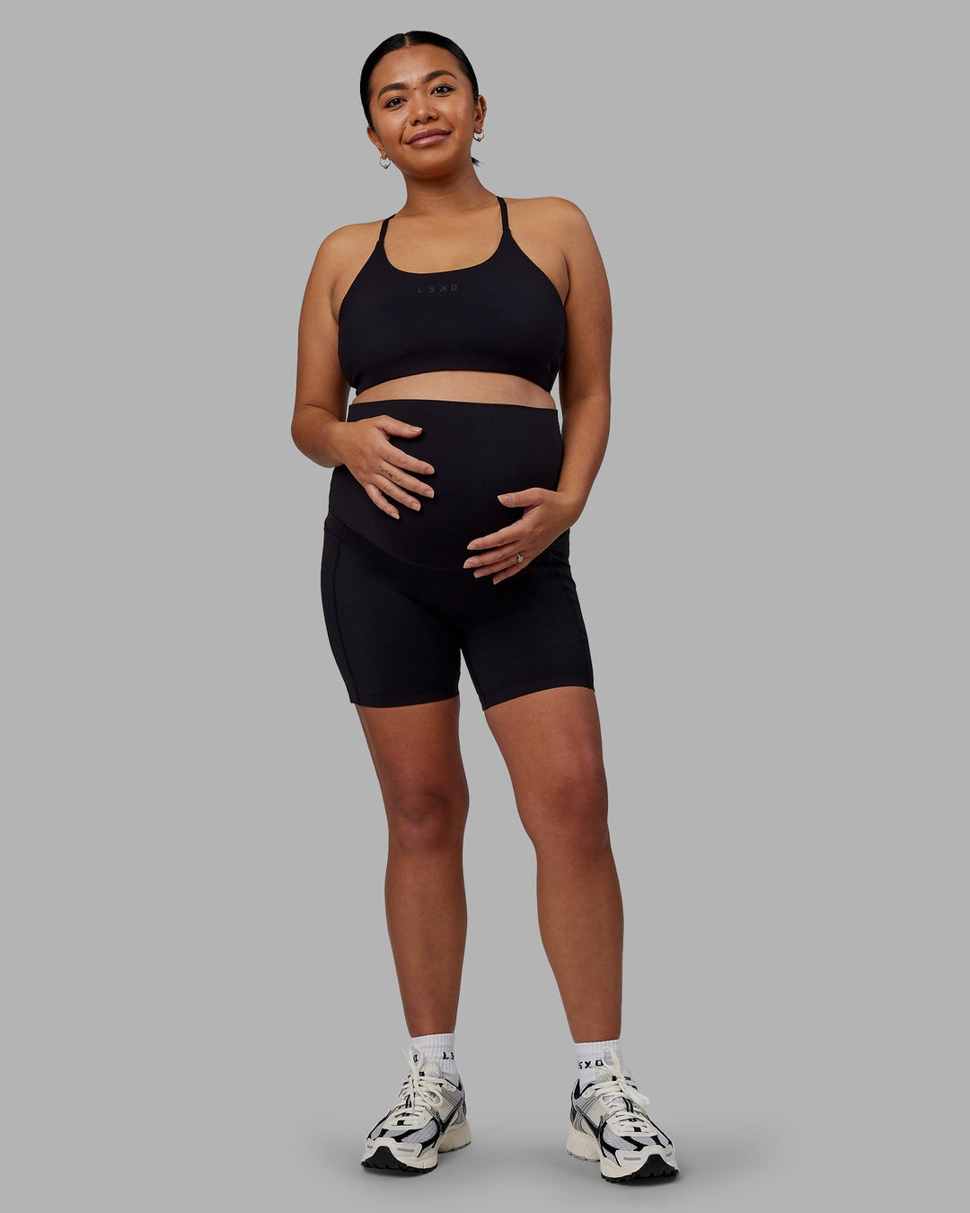 Woman wearing Elixir Ultra High-Rise Maternity 6" Short Pockets - Black | Model:Jojo | Size:M