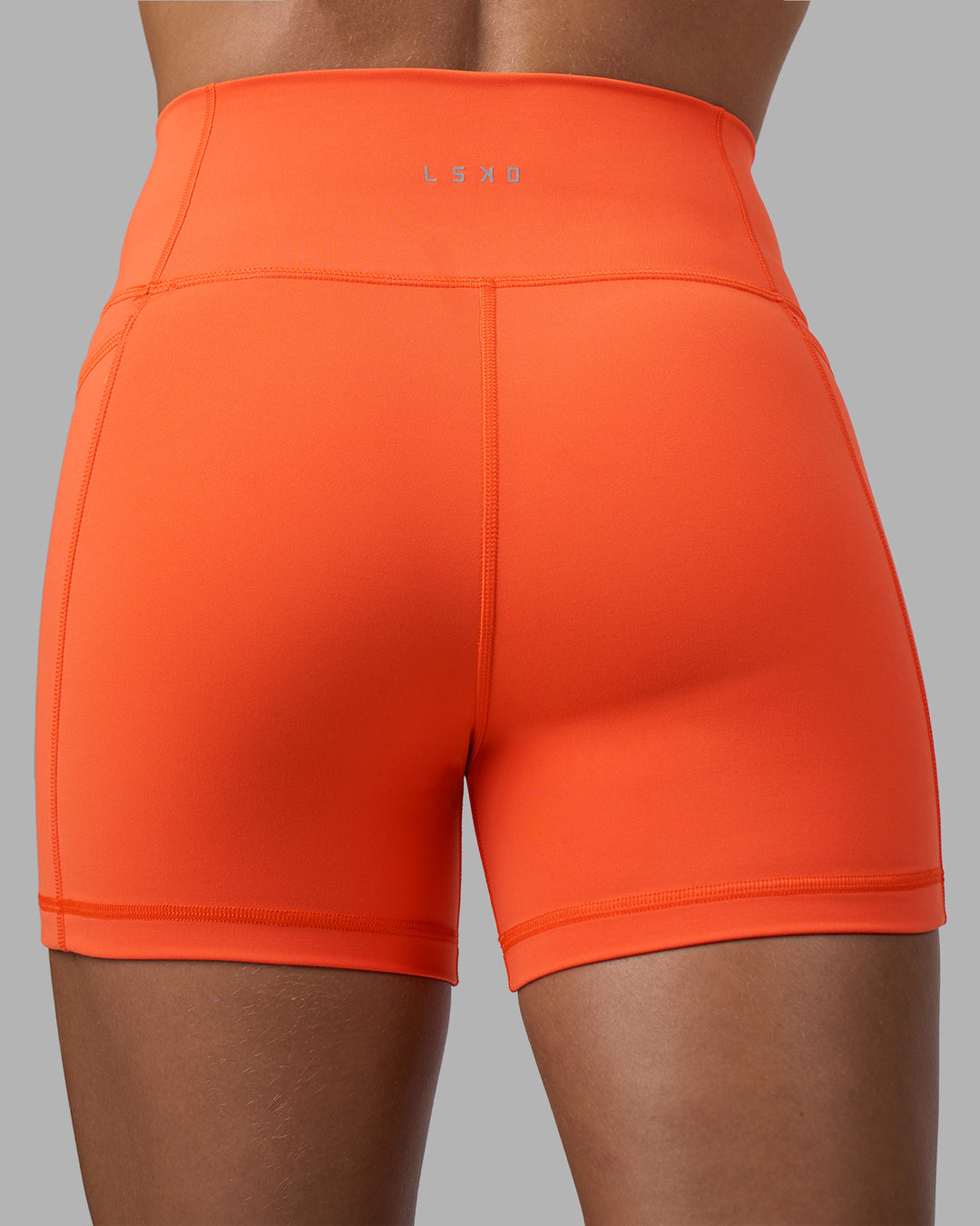 Woman wearing Fusion Ultra High-Rise 4" Short Pockets - Ultra Orange | Model:Katie | Size:S