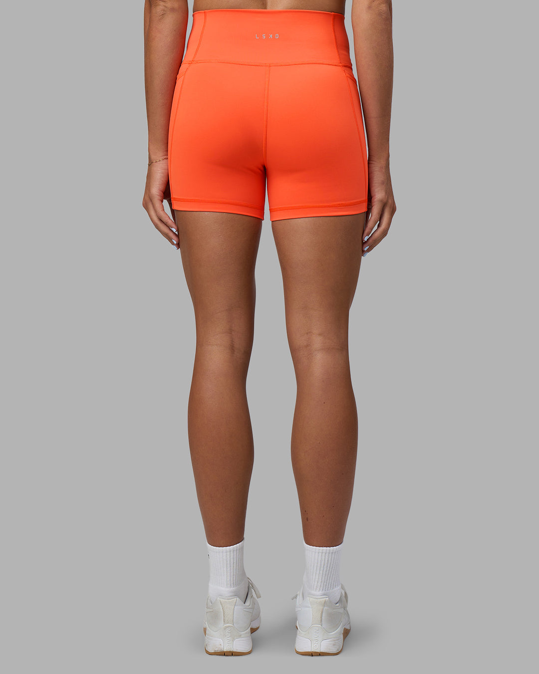 Woman wearing Fusion Ultra High-Rise 4" Short Pockets - Ultra Orange | Model:Katie | Size:S