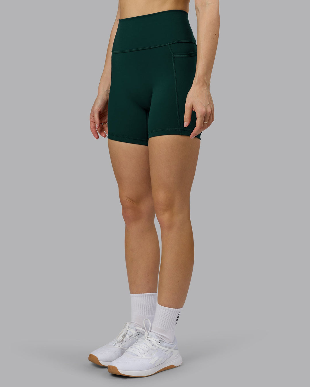 Woman wearing Fusion Ultra High-Rise 6" Short Pockets - Dark Moss | Model:Emilie | Size:S