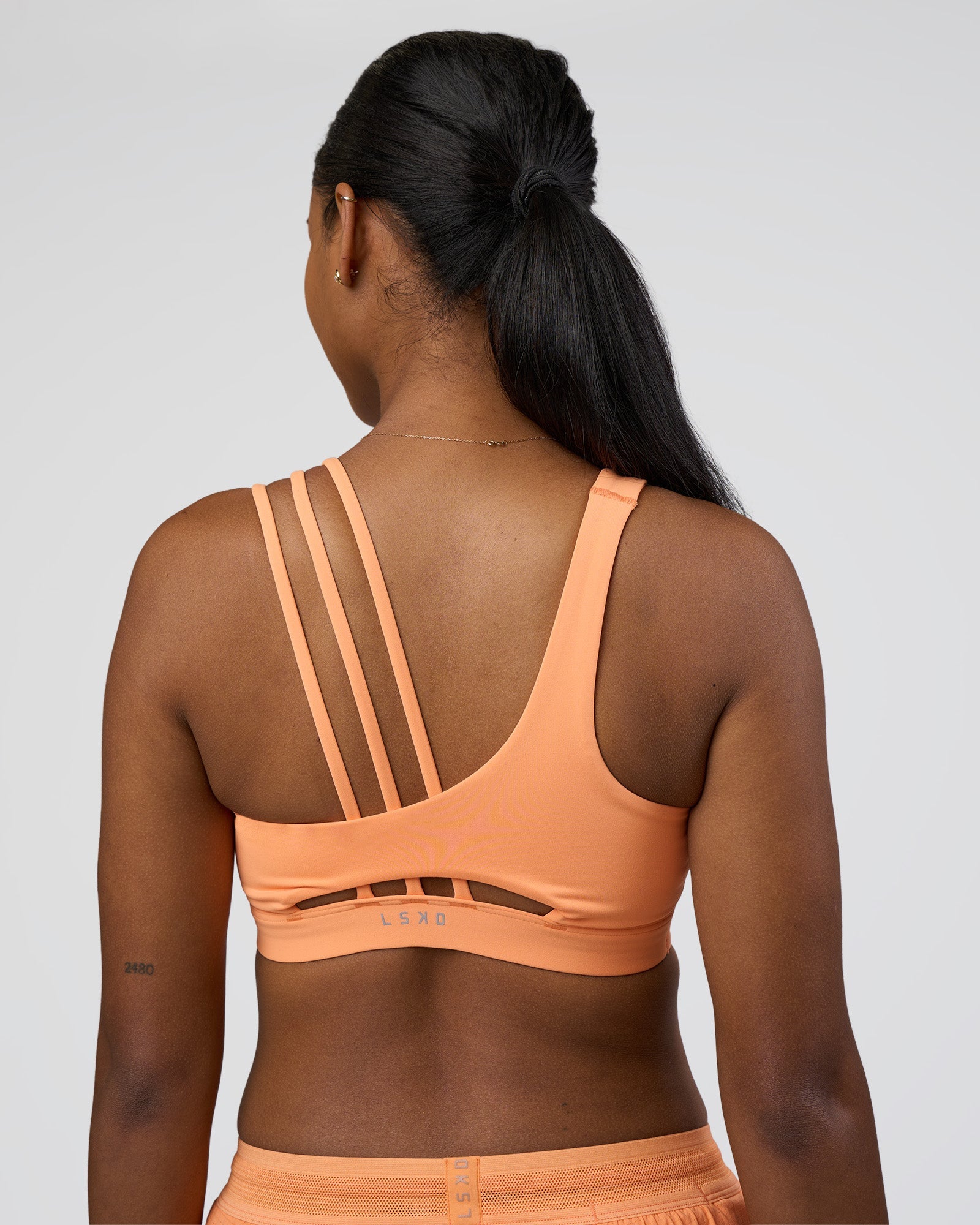 Woman wearing Galvanise Splice Sports Bra - Cantaloupe | Model:Rica | Size:S
