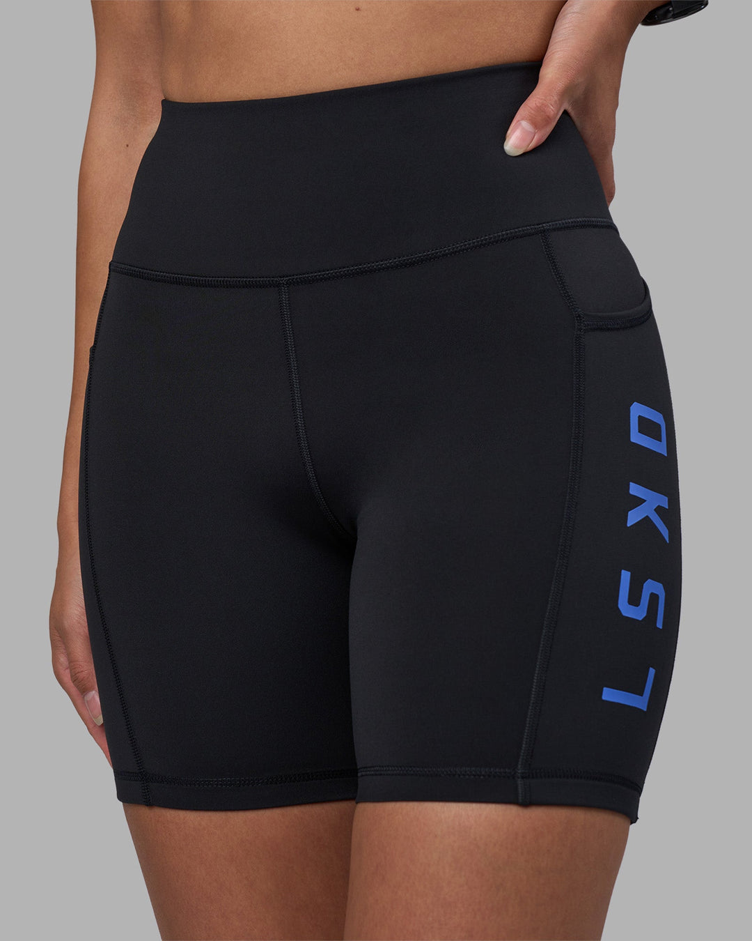 Woman wearing Rep Ultra High-Rise 6" Short Pockets - Black-Power Cobalt | Model:Rhiley | Size:S