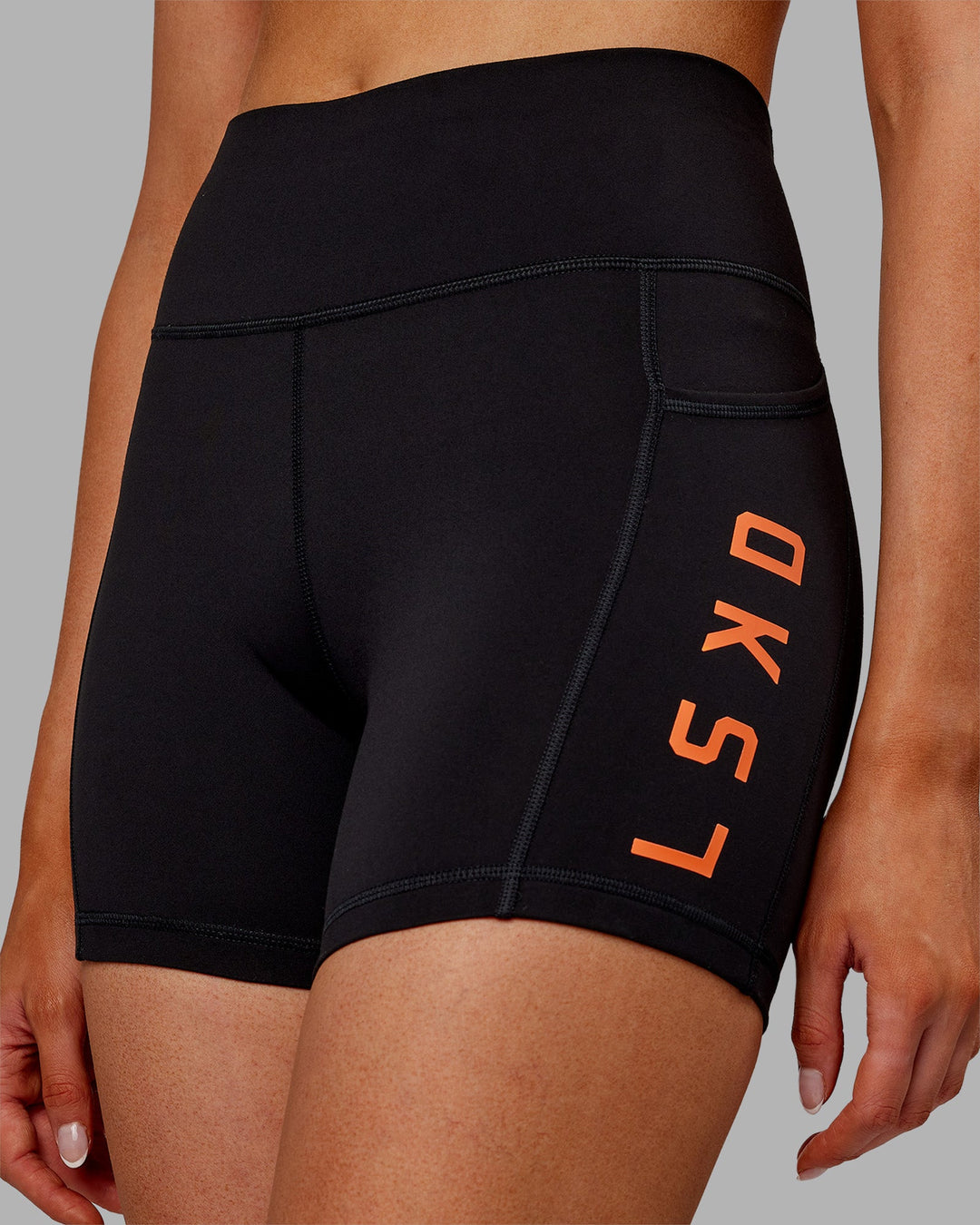 Woman wearing Rep Ultra High-Rise 4" Short Pockets - Black-Ultra Orange | Model:Ella | Size:S