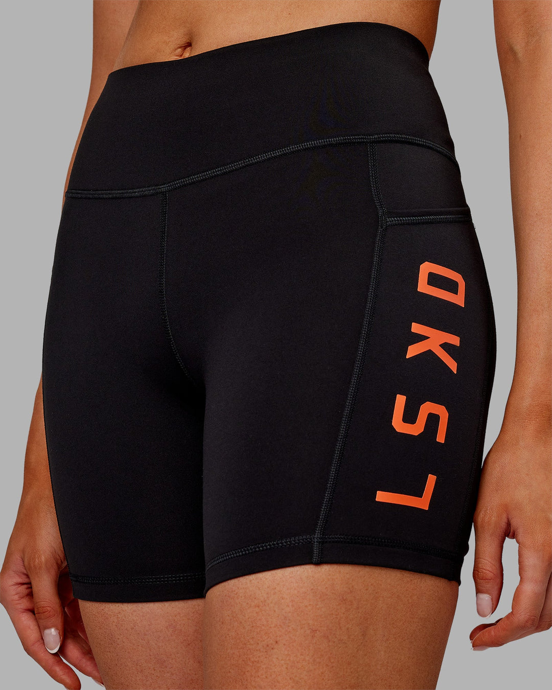Woman wearing Rep Ultra High-Rise 6" Short Pockets - Black-Ultra Orange | Model:Ella | Size:S