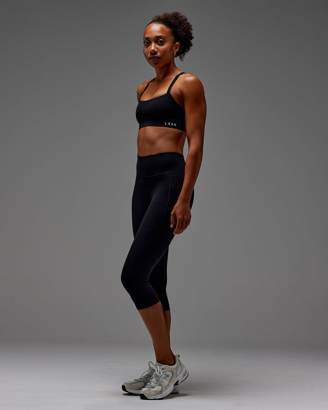 Woman wearing Fusion Ultra High-Rise 3/4 Legging Pockets - Black | Model:Txai | Size:XS