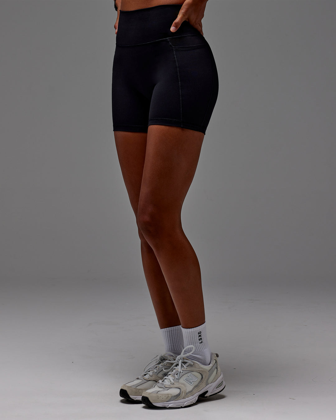 Woman wearing Fusion Ultra High-Rise 6" Short Pockets - Black | Model:Txai | Size:XS