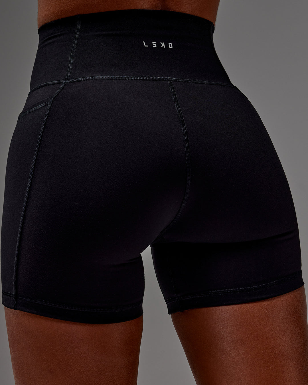 Woman wearing Fusion Ultra High-Rise 6" Short Pockets - Black | Model:Txai | Size:XS