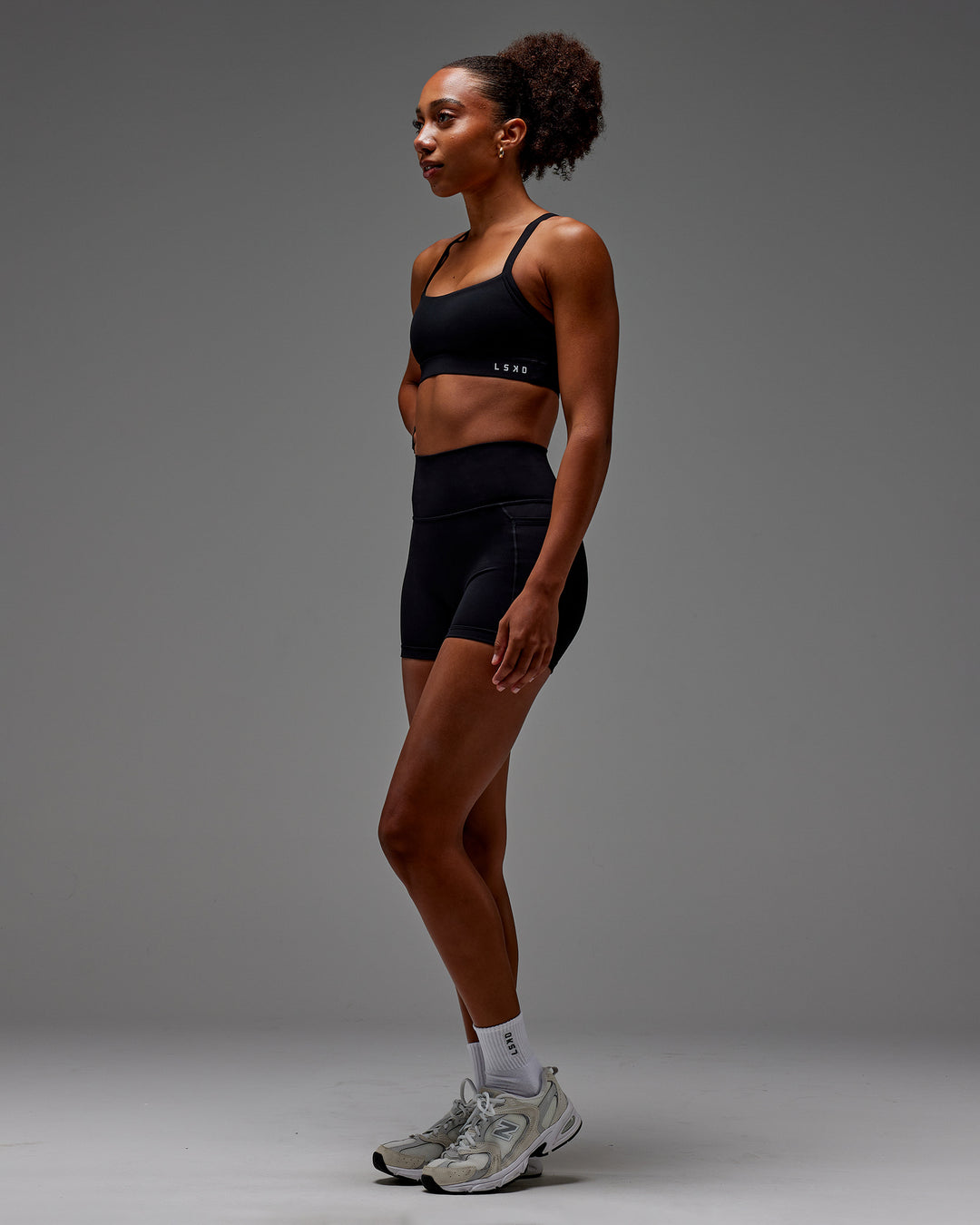 Woman wearing Fusion Ultra High-Rise 4" Short Pockets - Black | Model:Txai | Size:XS