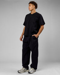 Man wearing 86 V-Neck Oversized Tee - Black-Black | Model:Leandro | Size:M