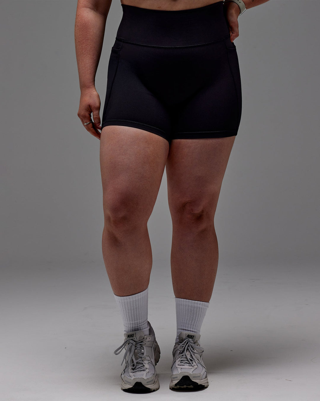 Woman wearing Fusion Mid Short Tight With Pockets in Black | Model:Caity | Size:M