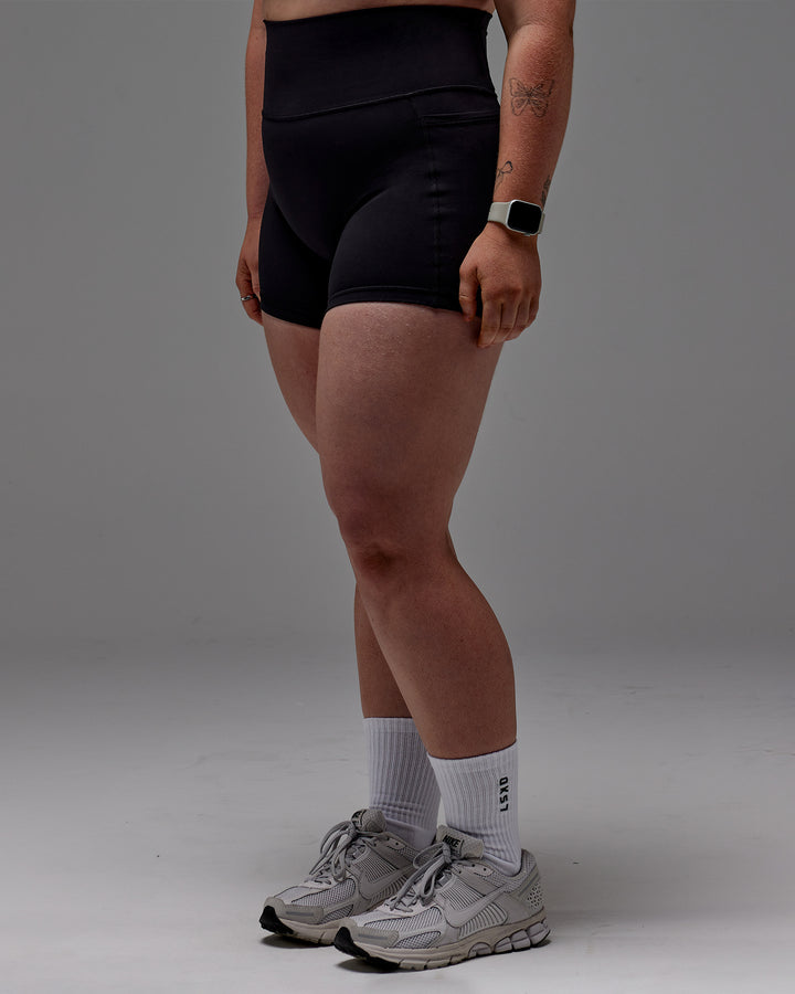 Woman wearing Fusion Mid Short Tight With Pockets in Black | Model:Caity | Size:M
