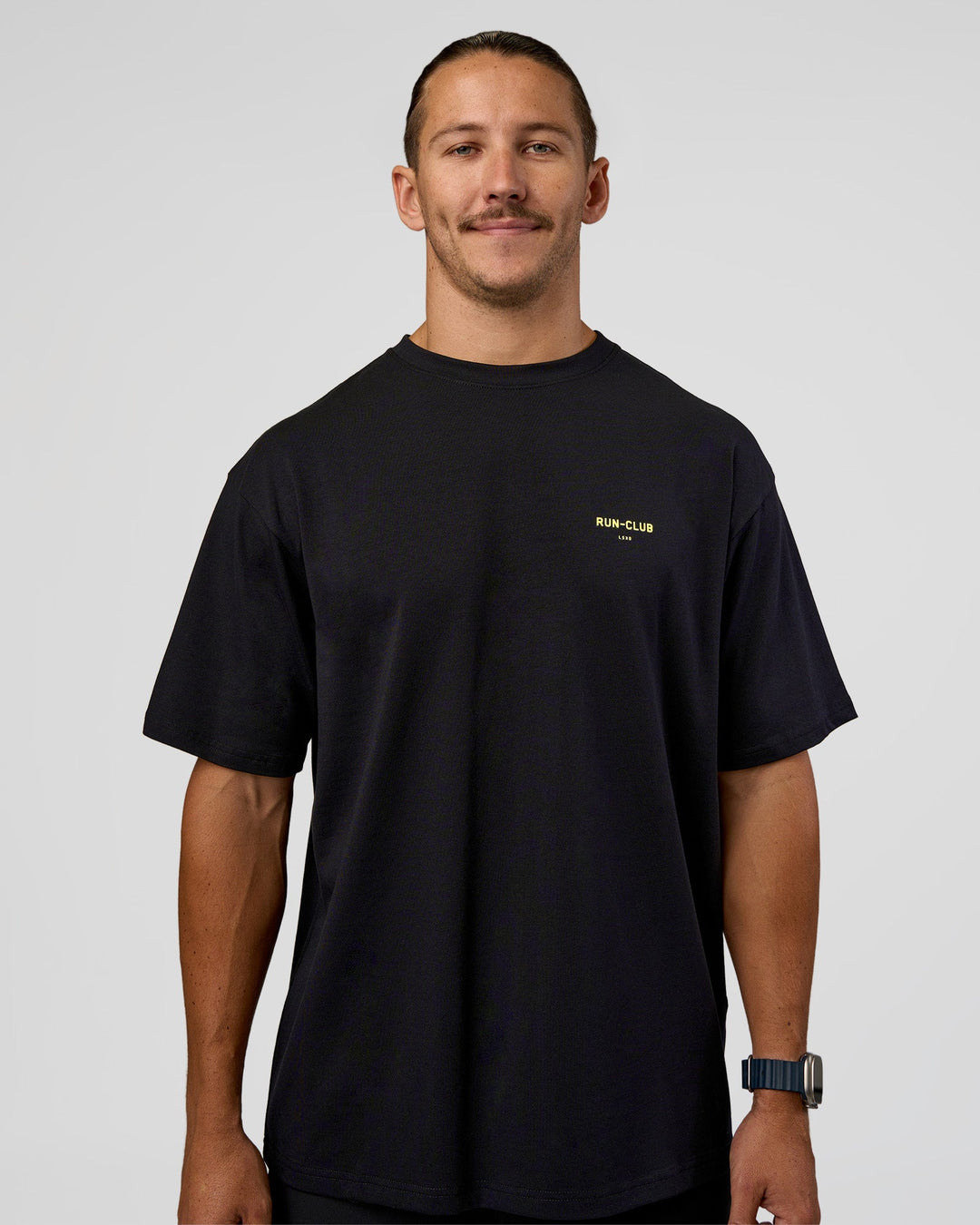 Man wearing RUN CLUB FLXCotton Tee Oversize - Black-Yellow Fizz | Model:Jaiden | Size:M