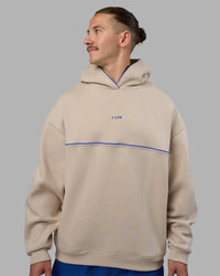 Man wearing Unisex Oversized Piping Hoodie - Shale Beige-Power Cobalt | Model:Jaiden | Size:M