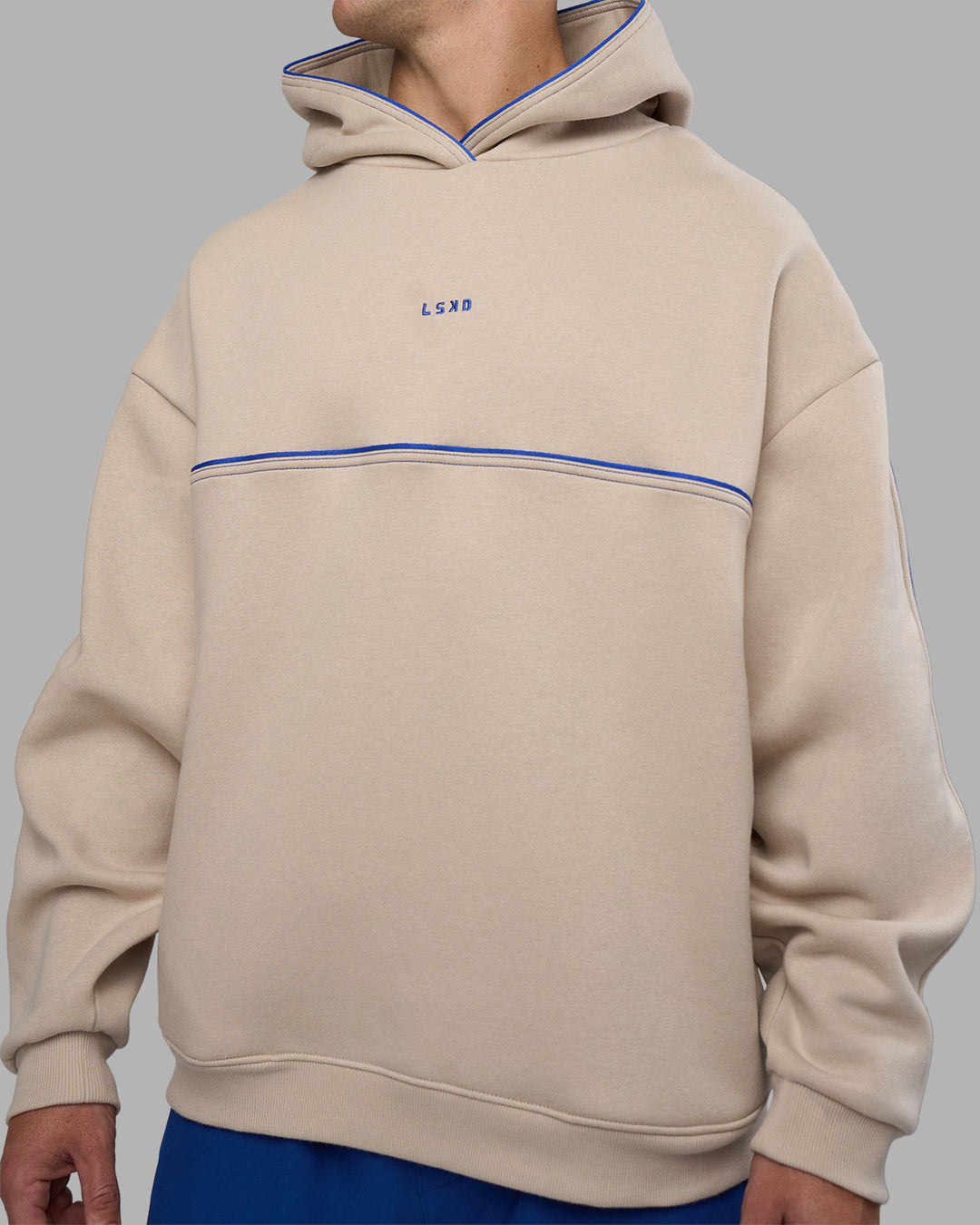 Man wearing Unisex Oversized Piping Hoodie - Shale Beige-Power Cobalt | Model:Jaiden | Size:M