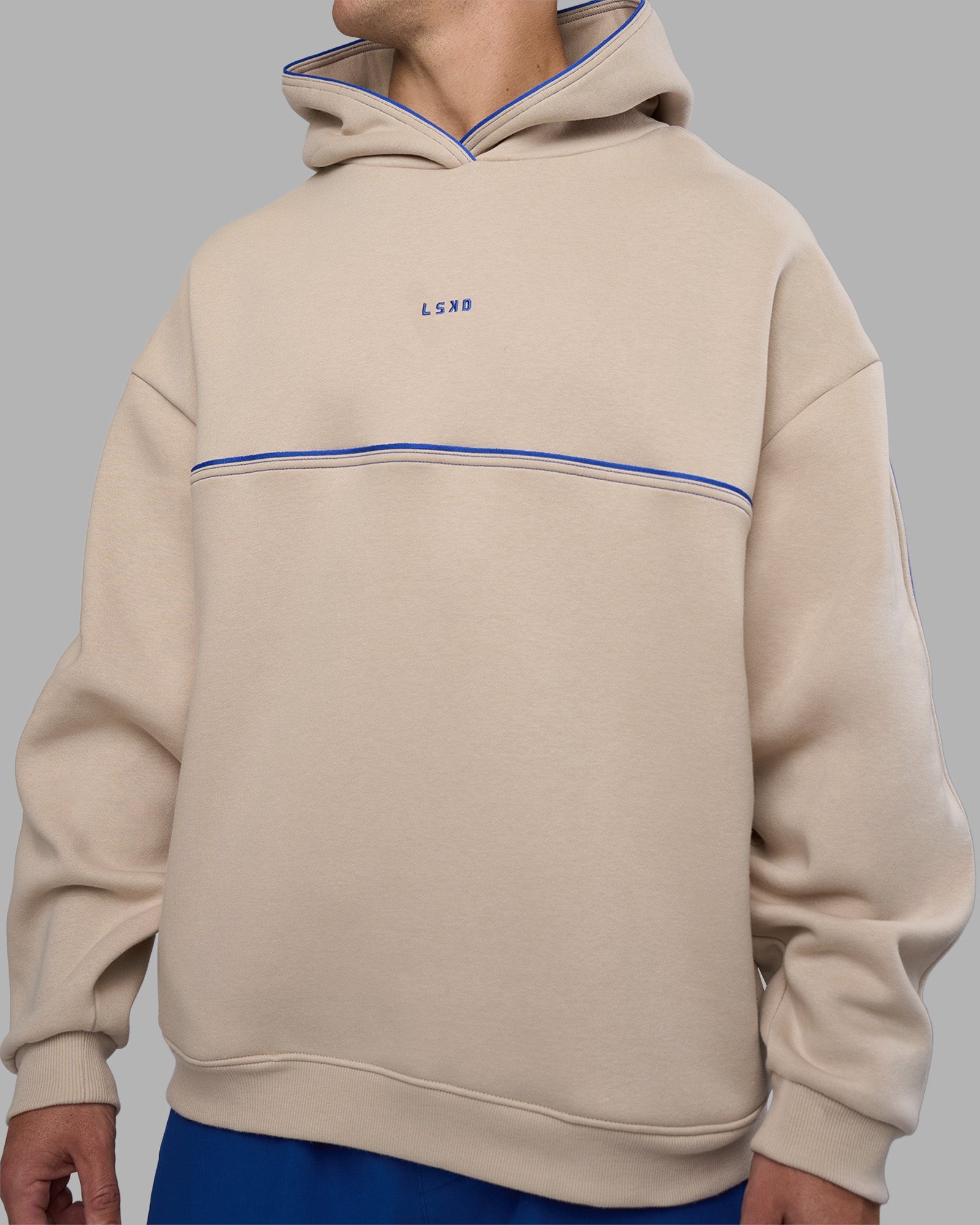 Man wearing Unisex Oversized Piping Hoodie - Shale Beige-Power Cobalt | Model:Jaiden | Size:M