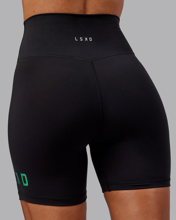 Woman wearing Evolved Mid-Length Shorts - Black-Impact Green
