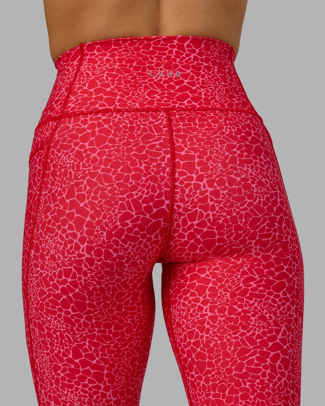 Woman wearing Fusion Ultra High-Rise 7/8 Legging Pockets - Red Vitality Print | Model:Halle | Size:S