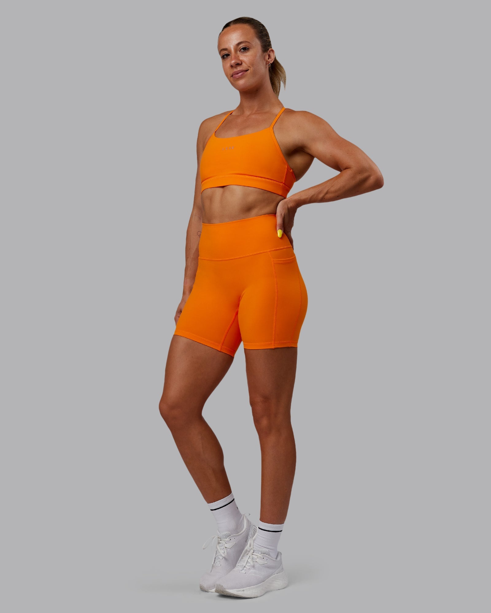 Woman wearing Fusion Ultra High-Rise 6" Short Pockets - Vibrant Orange | Model:Bree | Size:S