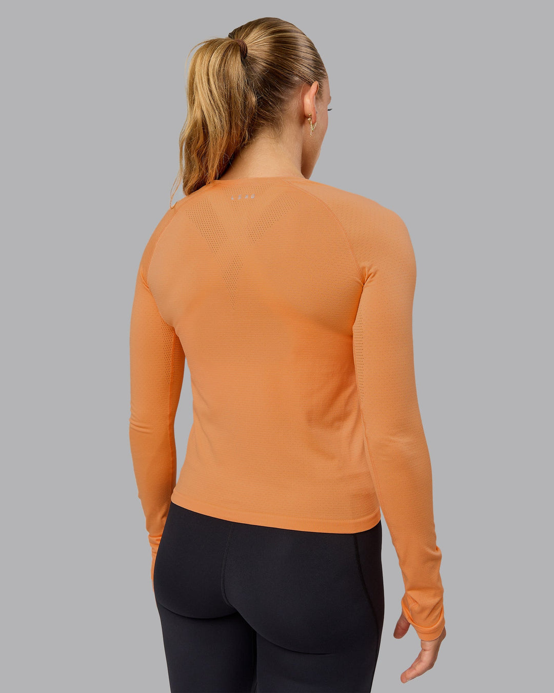 Woman wearing AeroFLX+ Seamless Long Sleeve Tee - Cantaloupe