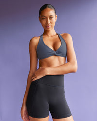 Woman wearing Aspire Twist Sports Bra - Night Shadow | Model:Tali | Size:S | Thumbnail Index: 0