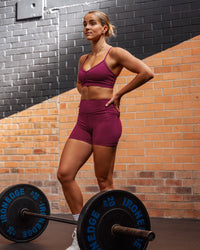 Woman wearing Elite High-Rise 4" Short Pockets - Plum Berry | Size:S