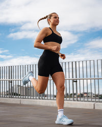 Woman wearing Elite Run High-Rise 7" Short Pockets - Black | Model:Ali | Size:S