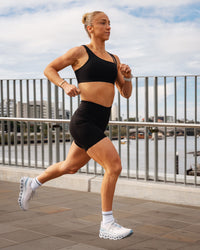 Woman wearing Elite Run High-Rise 7" Short Pockets - Black | Model:Bronte | Size:S