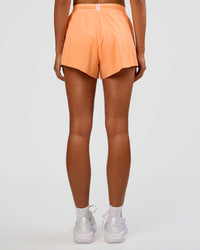 Woman wearing Accelerate 3" High-Rise Running Short - Cantaloupe-Marshmallow | Set:true | Angle:back | Model:Ruby | Size:S