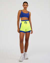Woman wearing Accelerate 3" High-Rise Running Short - Electric Indigo-Lime Glo | Model:Ruby | Size:S