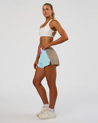 Woman wearing Accelerate 3" High-Rise Running Short - Taupe Ash-Glacial Blue | Model:Emelia | Size:S