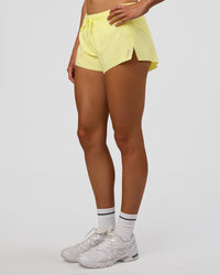 Woman wearing Accelerate 3" Mid-Rise Running Short - Yellow Fizz | Set:true | Angle:side | Model:Evie | Size:S