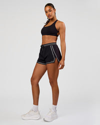 Woman wearing Accelerate 3" Reflective High-Rise Running Short - Black-Reflective | Model:Rosie | Size:S