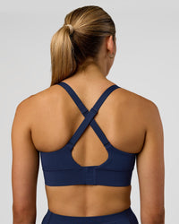 Woman wearing Accelerate Sports Bra - Future Navy | Set:true | Angle:back | Model:Evie | Size:S
