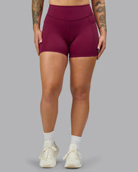 Woman wearing Elite High-Rise 4" Short Pockets - Plum Berry | Model:Robyn | Size:S