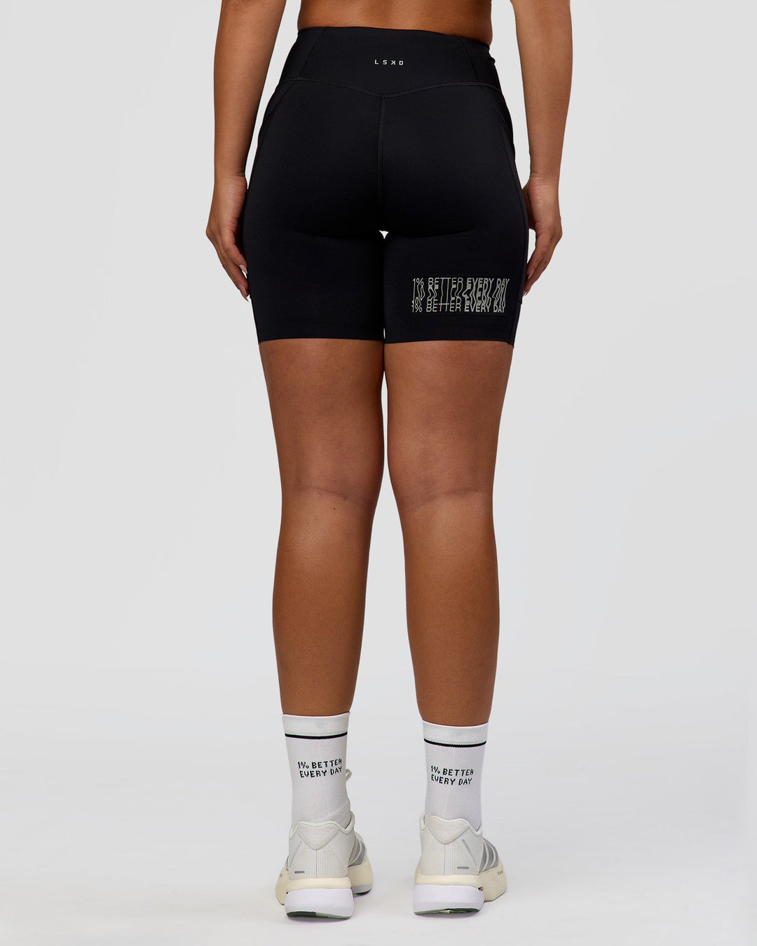 Woman wearing Elite Hype Reflective Run High-Rise 7" Short Pockets - Black-Hype Reflective | Model:Sophia | Size:S