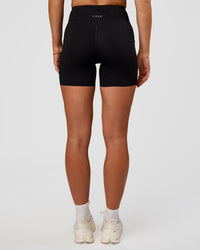 Woman wearing Elite Run High-Rise 5" Short Pockets - Black | Model:Emelia | Size:S