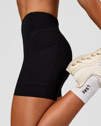 Woman wearing Elite Run High-Rise 5" Short Pockets - Black | Model:Emelia | Size:S