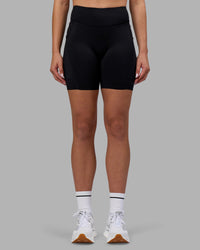 Woman wearing Elite Run High-Rise 7" Short Pockets - Black | Model:Charlize | Size:S