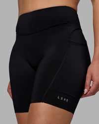 Woman wearing Elite Run High-Rise 7" Short Pockets - Black | Model:Charlize | Size:S